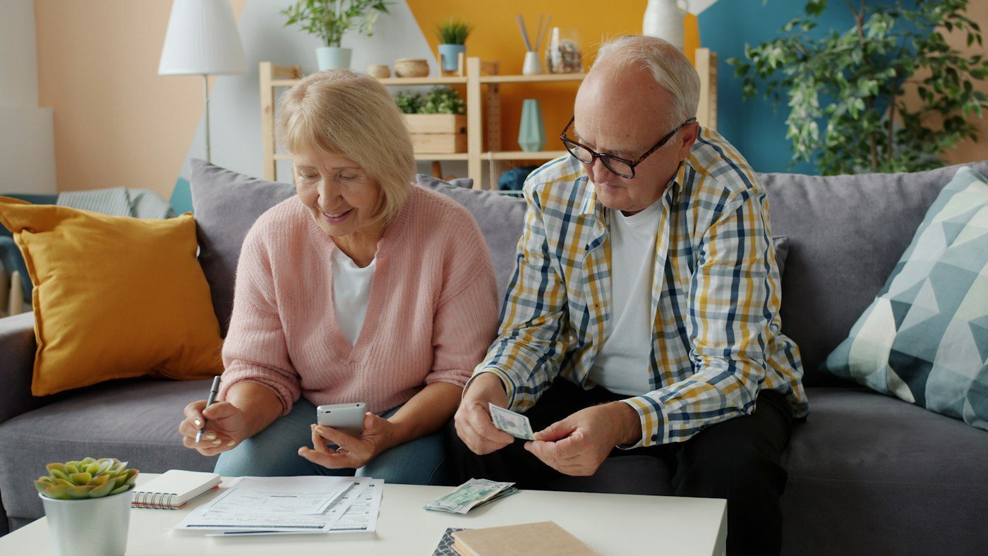 Retired couple going over their health plan costs on the couch